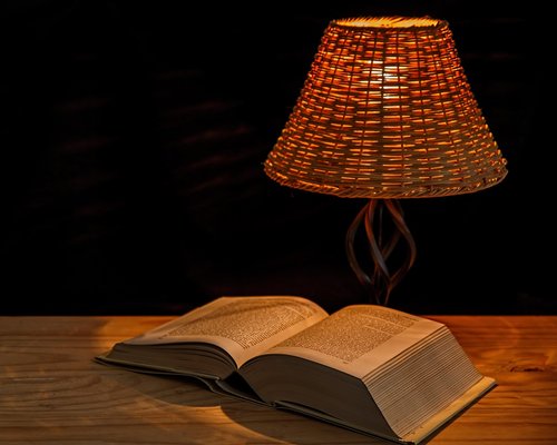 A cozy reading corner with an armchair and a warm directional desk lamp illuminating a book