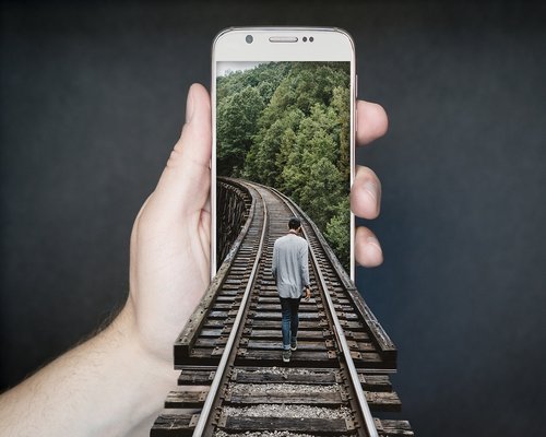 Hand holding a smartphone with lower brightness settings in a dimly lit room
