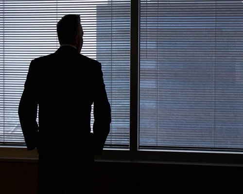 Woman looking thoughtfully out of a large office window away from her computer